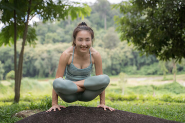 young woman practicing yoga beside a mountain by a stream in the morning.