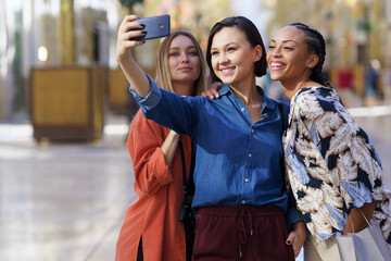 Joyful multiethnic women taking selfie on smartphone