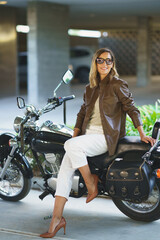 Attractive woman sitting on a vintage motorcycle. Caucasian woman in urban background.