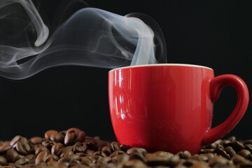 Fototapeta premium Tazzina di caffe caldo fumante e chicchi di caffè sul tavolo