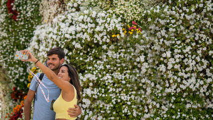 A young happy caucasian couple taking a photo in front of the Puppy sculpture in Bilbao