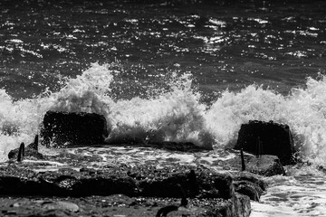 sea waves with foam and large stones. black and white beach photography