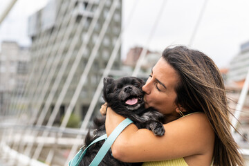 Woman kissing his pomeranian dog pet in the city of Bilbao