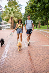 A young happy caucasian couple walking their dogs in a cloudy day in Spain in Bilbao and staring at the camera