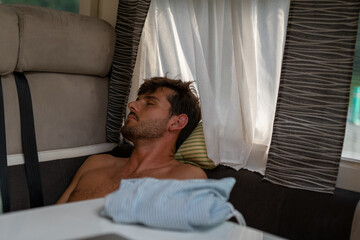 Caucasian young man sleeping and resting in the sofa of the motor home, van.