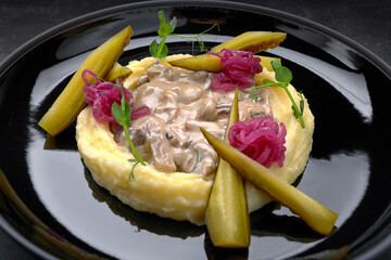 Mashed potatoes with mushrooms in sauce and pickles