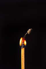 Matchstick burning in detail seen through a macro lens, black background, selective focus.
