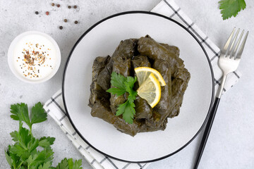 Dolma, sour cream, lemon, parsley on a gray background. Traditional Caucasian, Turkish, Armenian and Greek cuisine