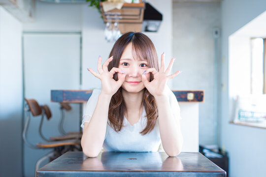 お茶目に両手で頬にOKのサインをする日本の若い女性
