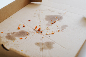 Eaten pizza, greasy traces and food crumbs on a cardboard box
