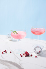 Winter holidays festive alcohol pink cocktails with peace of pomegranate in the marble table, winter drink concept, New Year holidays, front view