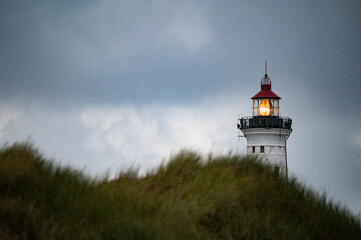 Nørre Lyngvig lighthouse behind a dune with grey sky