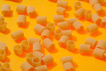 raw pasta on a bright yellow background. Food pattern