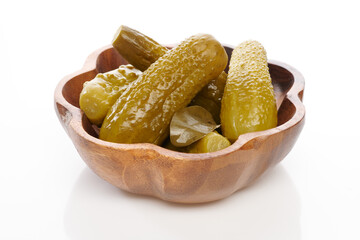 Cornichons, pickled cucumbers in wooden bowl over white