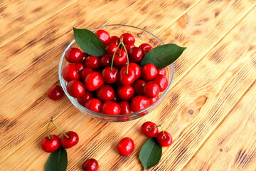 Fresh cherries in transparent plate on wooden table. Red berry cherry, harvesting