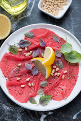 Middle close-up of carpaccio made of raw marbled beef, vertical shot, selective focus