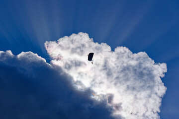 Swiss Army parachutist up in the air in backlight with god rays at Axalp, Canton Bern, on a blue cloudy autumn day. Photo taken October 18th, 2022, Axalp, Switzerland.