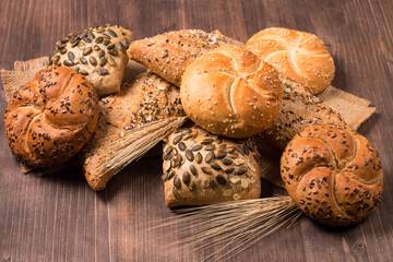 Assortment of baked bread with seeds on a wooden table background. Bakery. Food security concept.