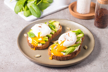 Toast with avocado, soft cream cheese, rye bread and poached Egg. Wholemeal open sandwich for healthy breakfast concept.