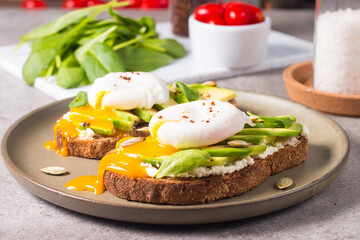 Toast with avocado, soft cream cheese, rye bread and poached Egg. Wholemeal open sandwich for healthy breakfast concept.
