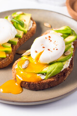 Toast with avocado, soft cream cheese, rye bread and poached Egg. Wholemeal open sandwich for healthy breakfast concept.