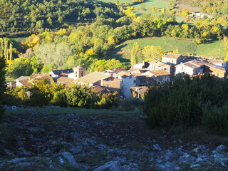el pequeño pueblo medieval de bonansa entre los colores de otoño con el campanario de la iglesia parroquial asomando entre los tejados, visto desde el mirador de la ermita, huesca, españa, europa