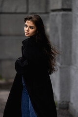 Fototapeta premium A young beautiful woman in a black coat