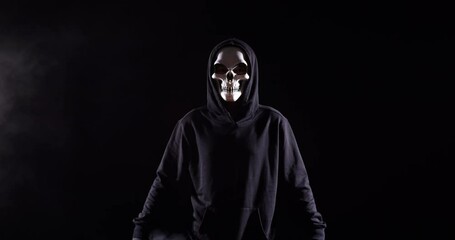 Scary Man In The Hooded Sweatshirt Wearing Halloween Mask Standing On The Black Background With Smoke
