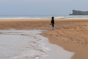 Woman strolling on Valdearenas Beach. Liencres, Cantabria