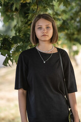 Portrait of a young beautiful fair-haired girl in dark clothes in the city in summer.