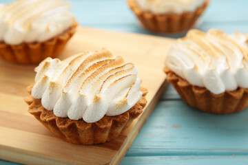 Appetizing lemon cupcakes with white cream on wooden board on blue background. Holiday, surprise, birthday, Valentine's Day.