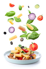 Plate with tasty pasta salad and falling ingredients on white background