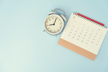 close up of calendar, alarm clock and pencil on the blue table background, planning for business meeting or travel planning concept