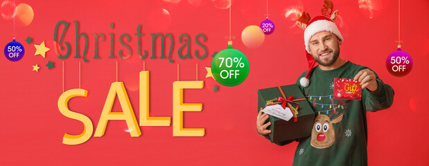 Handsome man with gift and voucher on red background. Christmas sale