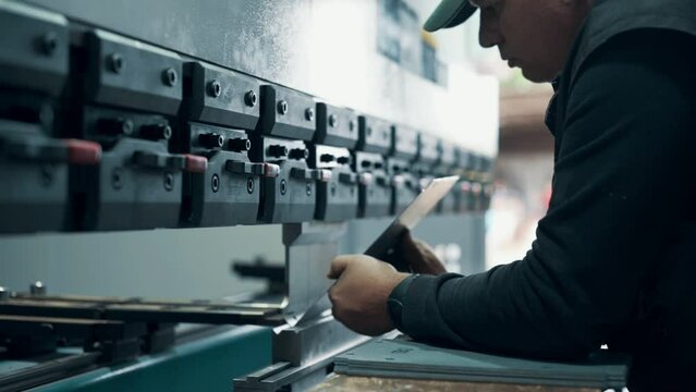 Press operator bending sheet metal. Close up.