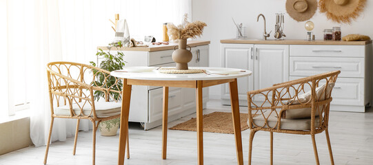 Interior of kitchen with dining table and rattan armchairs