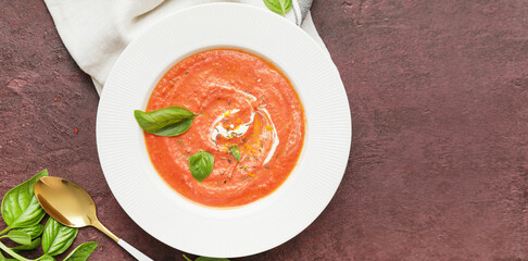Plate of tomato cream soup on color background