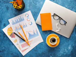 Business charts, gadgets and stationery on blue background