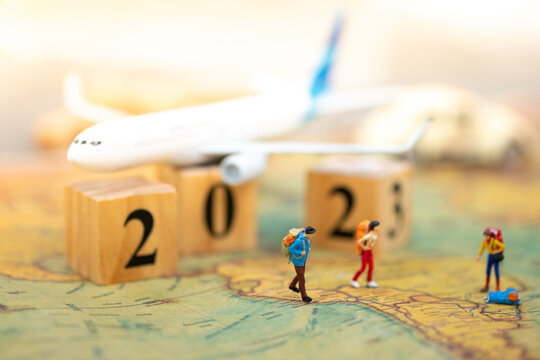 Miniature people: backpacker stack of vintage map with wooden box 2023 using as business trip traveler adviser agency or explorer on earth background concept.