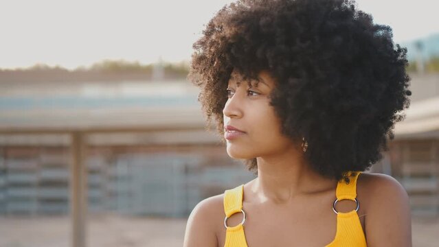 Cinematic video of a self confident young woman spending time in a modern city. Millennial girl with afro hairstyle lifestyle moments.