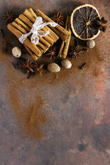 Christmas spices. Christmas composition with cinnamon sticks; anise stars, nutmeg, cloves, hazelnut and dried orange slices on dark background. Copy space for your text. Rustic vibe. - 540494380