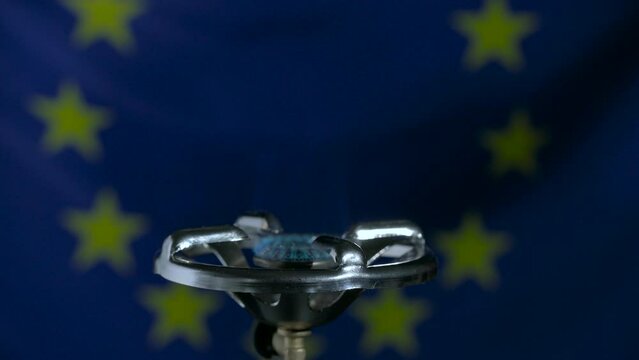 Natural gas burns in a gas burner against the background of the European Union flag, concept