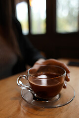 Woman drinking hot espresso at table in cafe