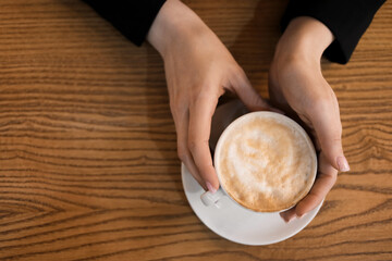 Woman drinking hot coffee on wooden background