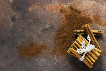 Cinnamon sticks and cinnamon powder on dark background. Copy space for your text. Christmas spices.