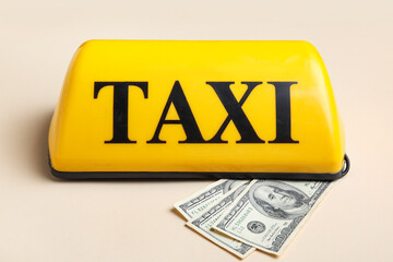 Yellow taxi roof sign and dollar banknotes on beige background