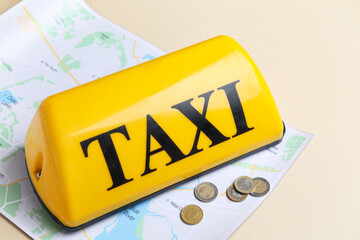 Yellow taxi roof sign, map and coins on beige background