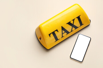 Yellow taxi roof sign and mobile phone on beige background