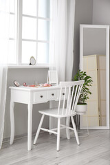 Modern makeup artist's workplace with decorative cosmetics near light wall in room interior