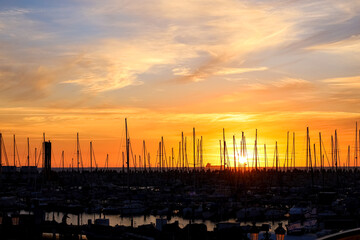 Yachts with masts against sky background at sunset